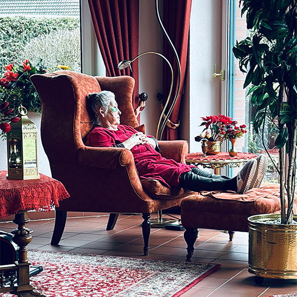 Annas Großmutter sitzt in einem Sessel und schaut in den Garten.