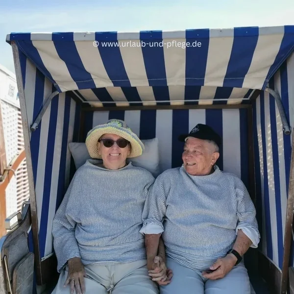 Urlaub & Pflege e. V. Erfahrungen: Zwei ältere Frauen sitzen lachend Hand in Hand im Strandkorb auf Norderney – Erinnerungsfoto nach fünfzig Jahren